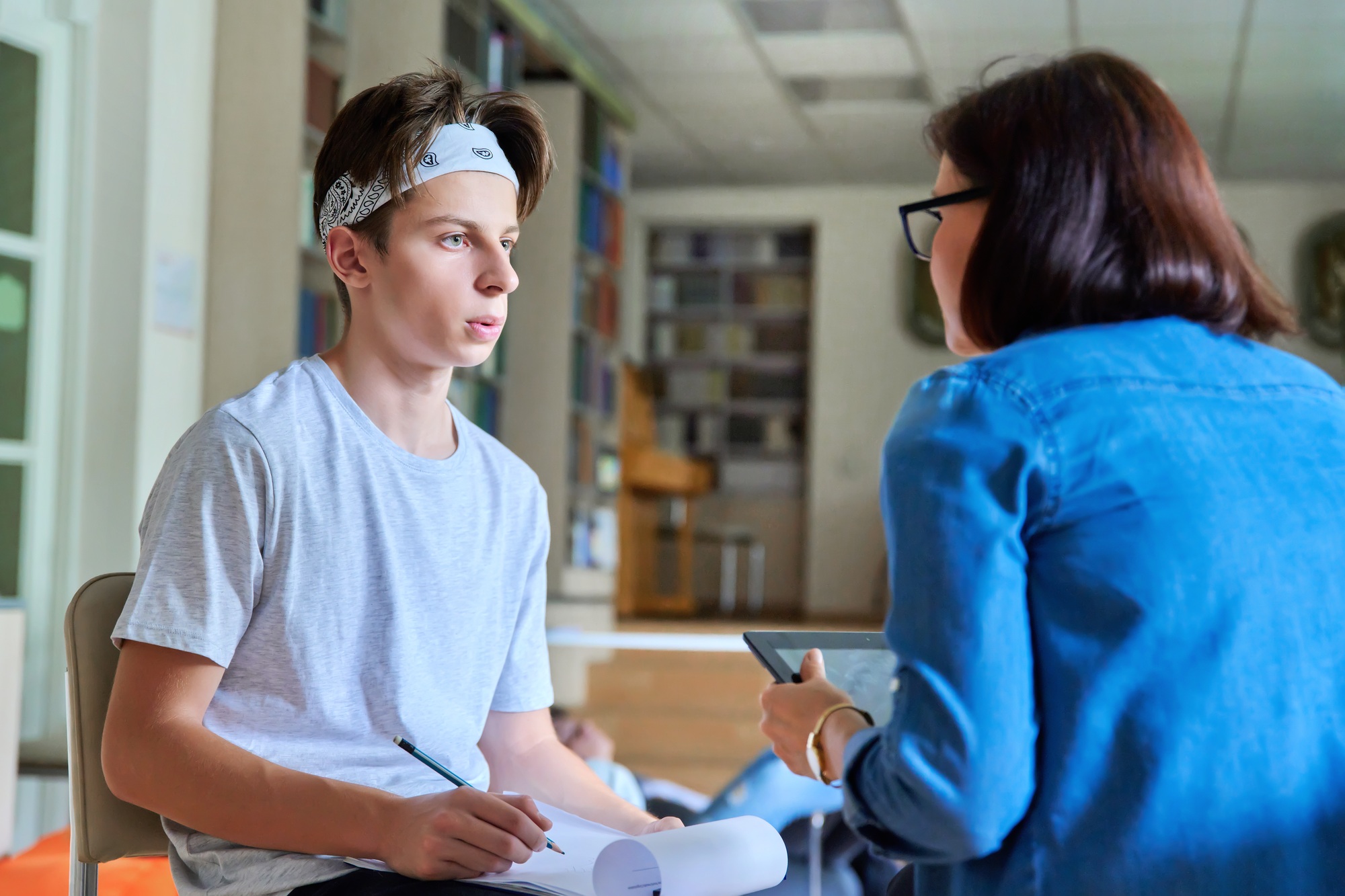Woman school psychologist talking and helping student, teenage boy